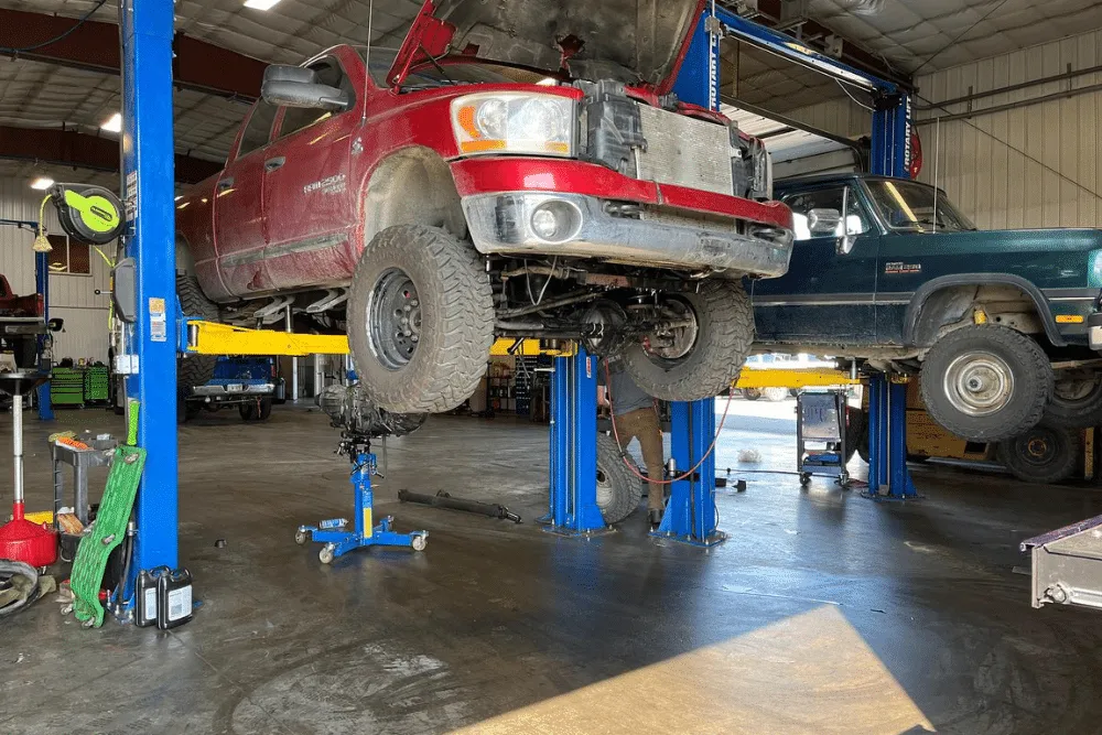 Wasilla Diesel Truck Repair, diesel repair in Palmer, AK at 1023 Diesel & Fleet. Red Dodge Ram 2500 lifted on a hydraulic lift in a diesel repair shop, undergoing major engine service.