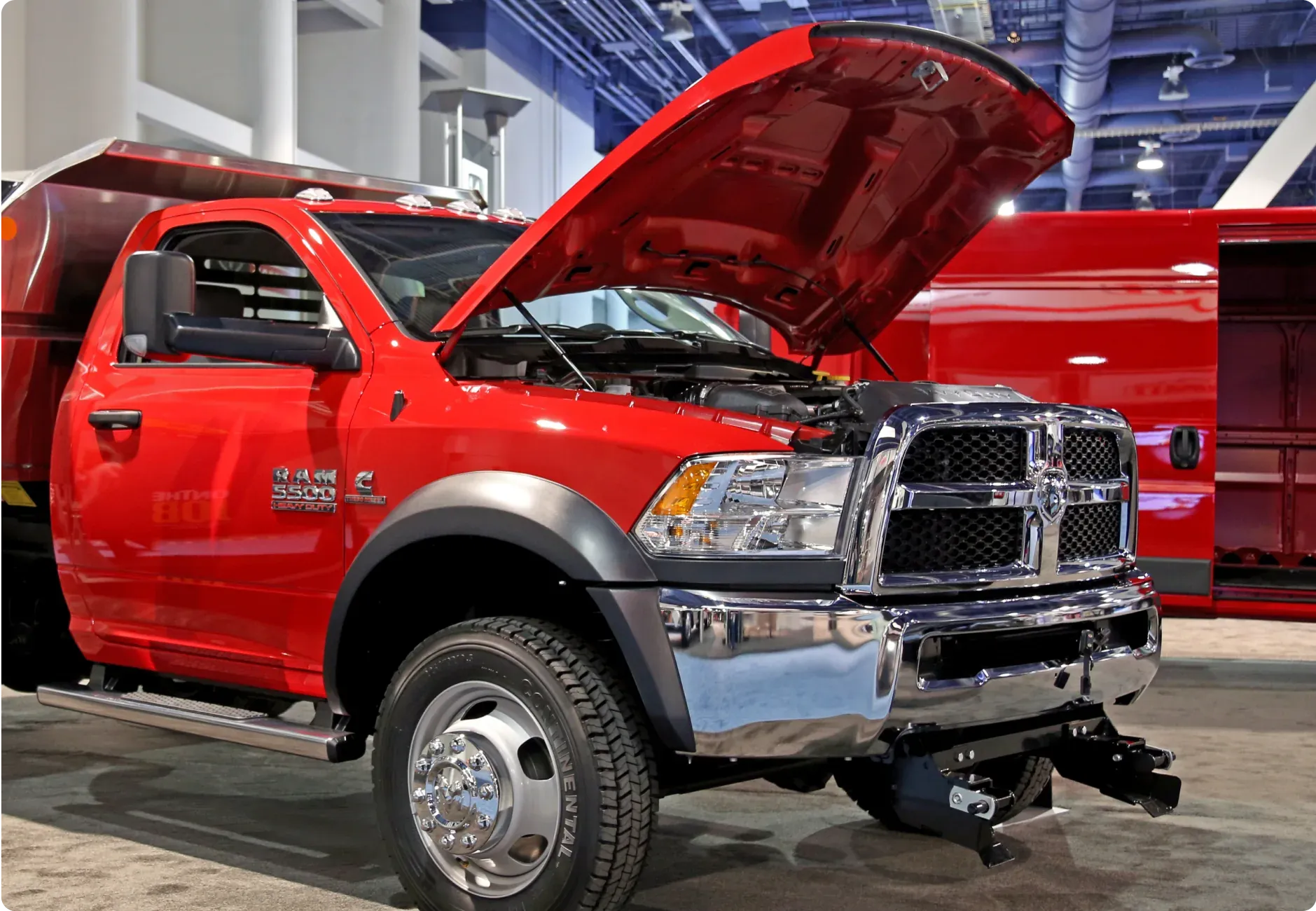 1023 Diesel & Fleet: a red RAM 5500 truck with its hood open and chrome accents displayed indoors.